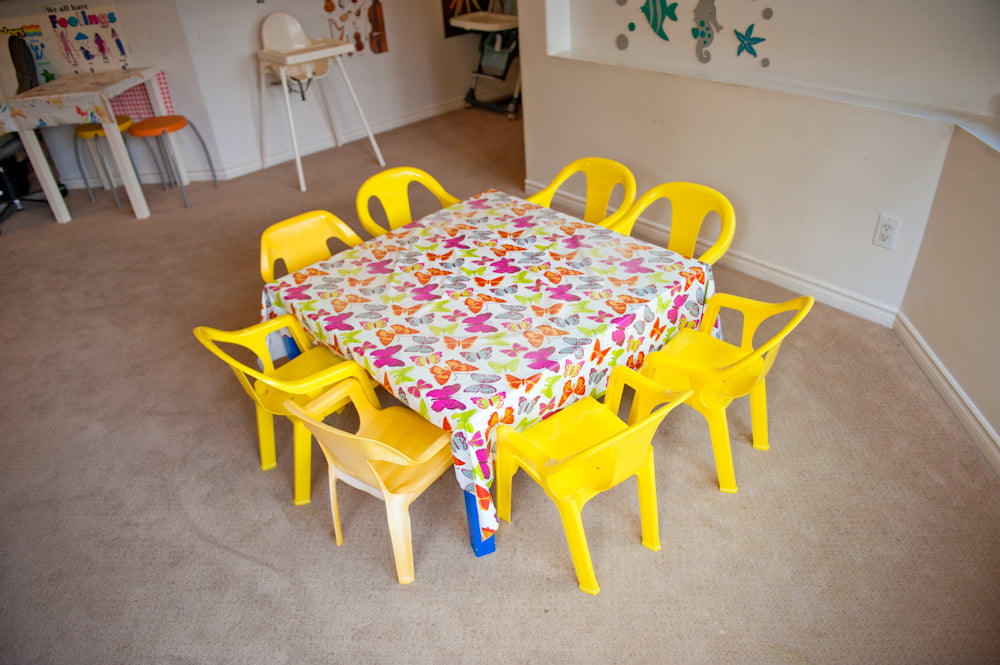 A yellow table and chairs set for art and lunch