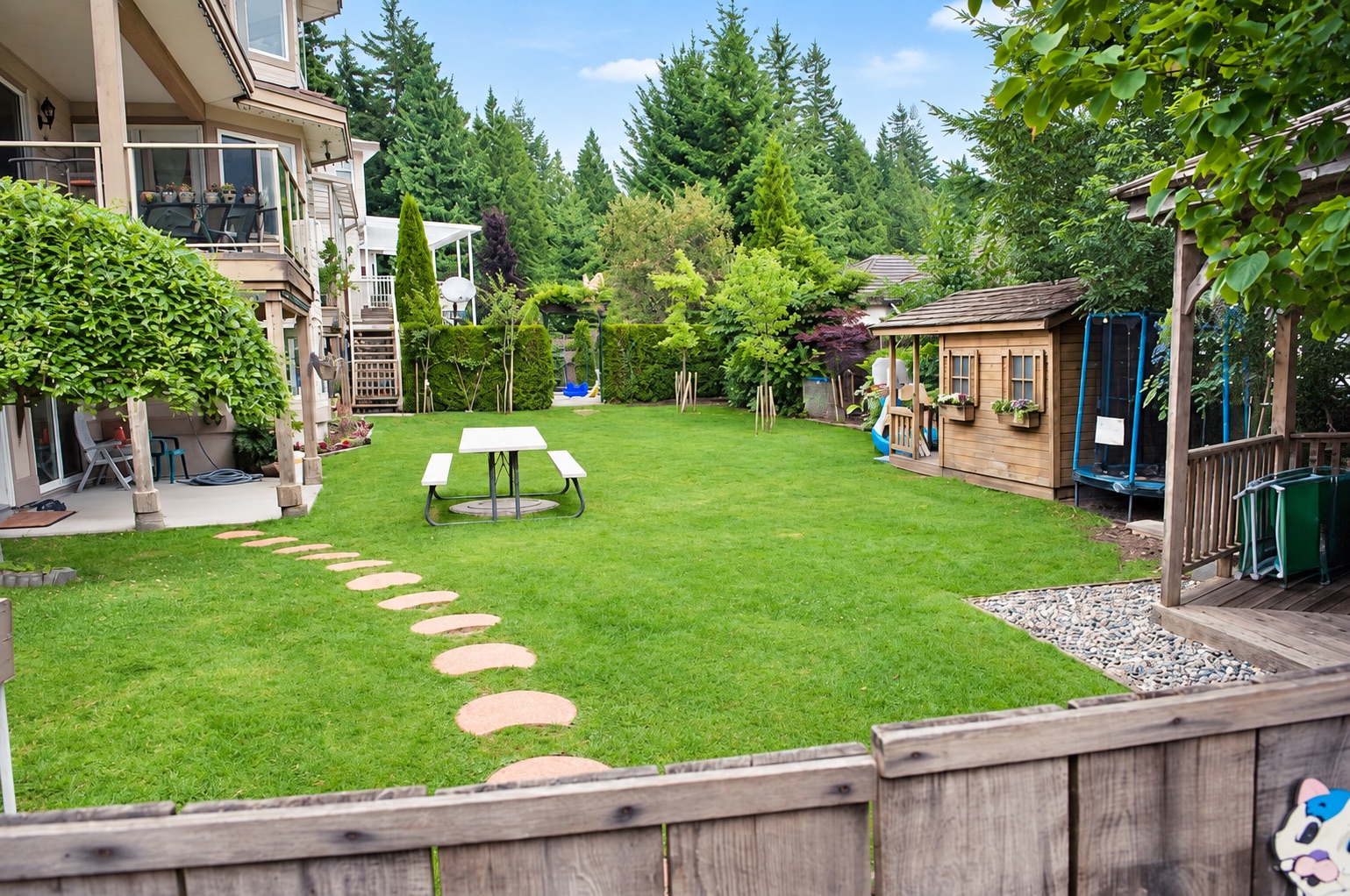 The large fenced backyard at Stars Childcare with lawn, path and trees
